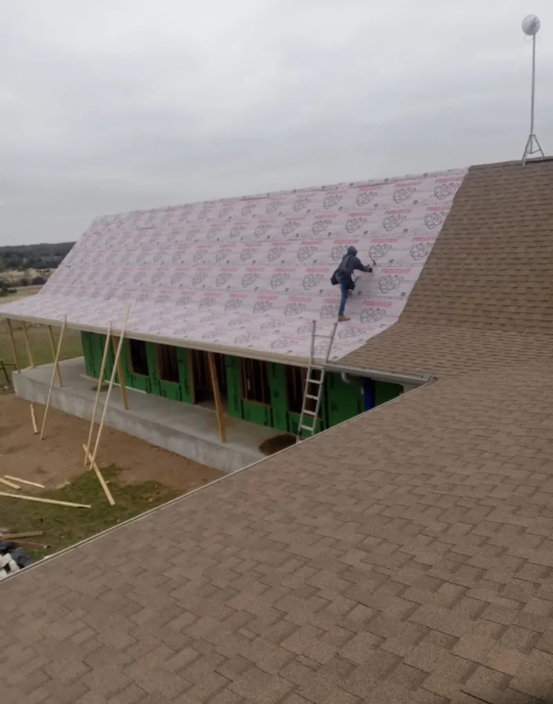 Worker preparing underlayment for a metal roof installation in Urbana